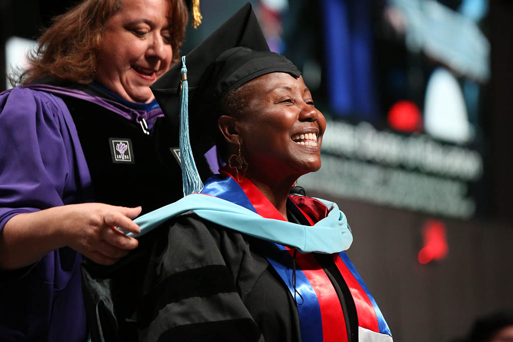 Female CPS Doctoral graduate presented with doctoral hood by their faculty adviser at the May 2022 CPS Doctoral Hooding Ceremony